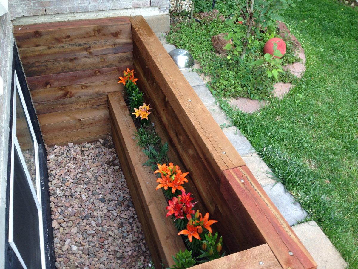 New wooden window well with orange lilies planted around it