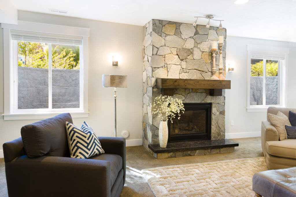 Beautiful basement living room with stone fireplace and natural light streaming through egress windows